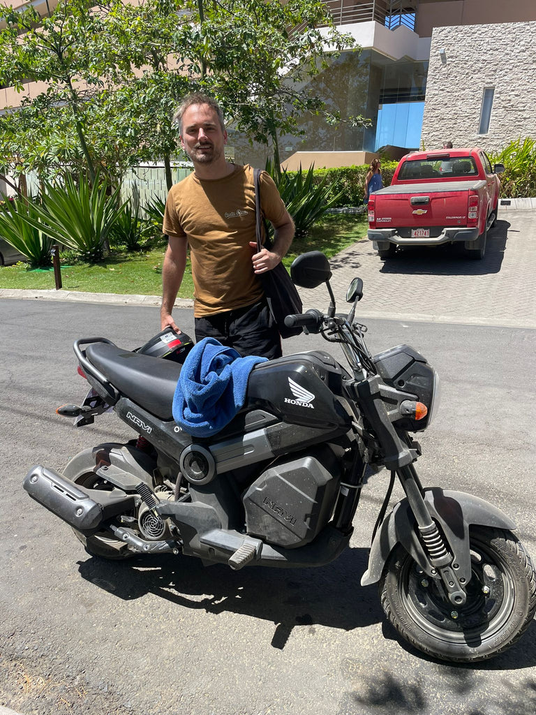 Ohana Rental Tamarindo Client Testimonial of James Lee standing next to a Honda Navi Scooter on a road along Tamarindo Heights